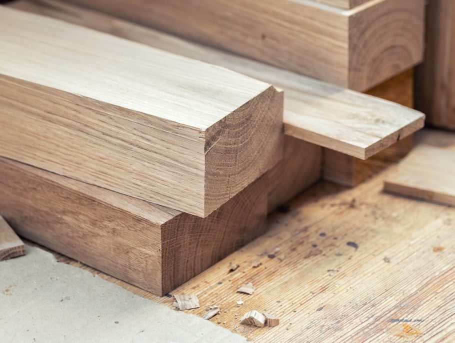 Oak wooden bar blocks materials stacked at carpentry woodwork workshop with tools and sawdust on background. Timber wood blanks at diy workbench. Close-up lumber beam details. Handcraft hobby