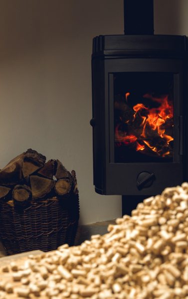 wooden pellets lie on a table in front of a fireplace with burning firewood